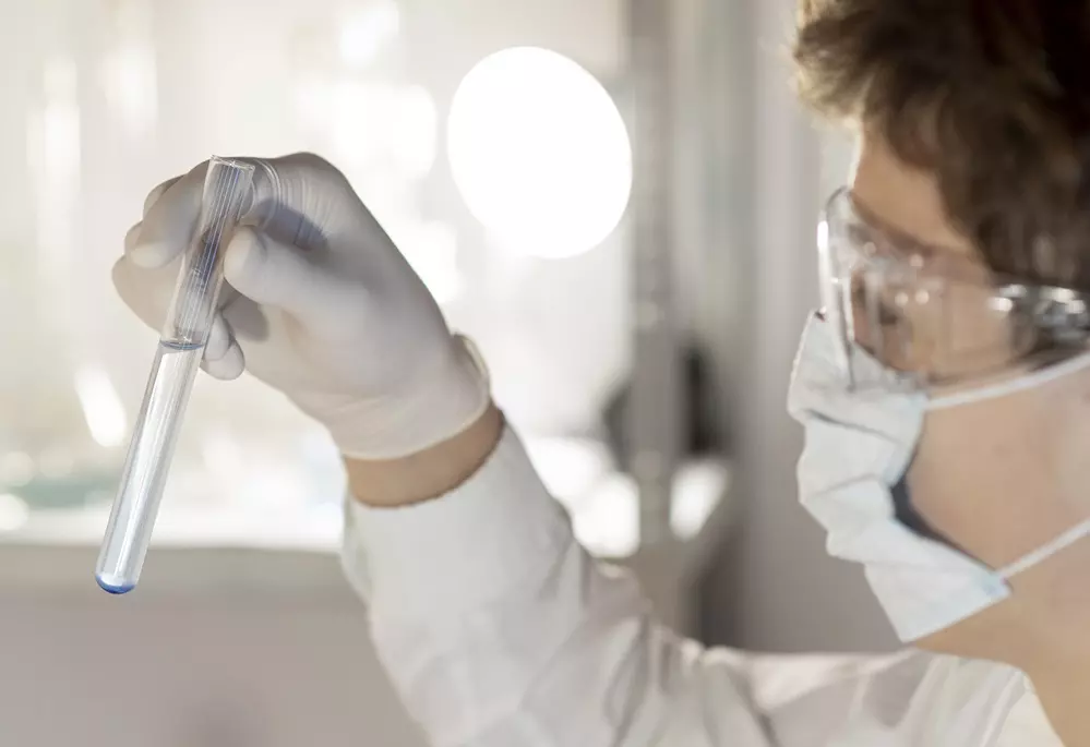 Osoba w laboratorium trzymająca próbkę wody.