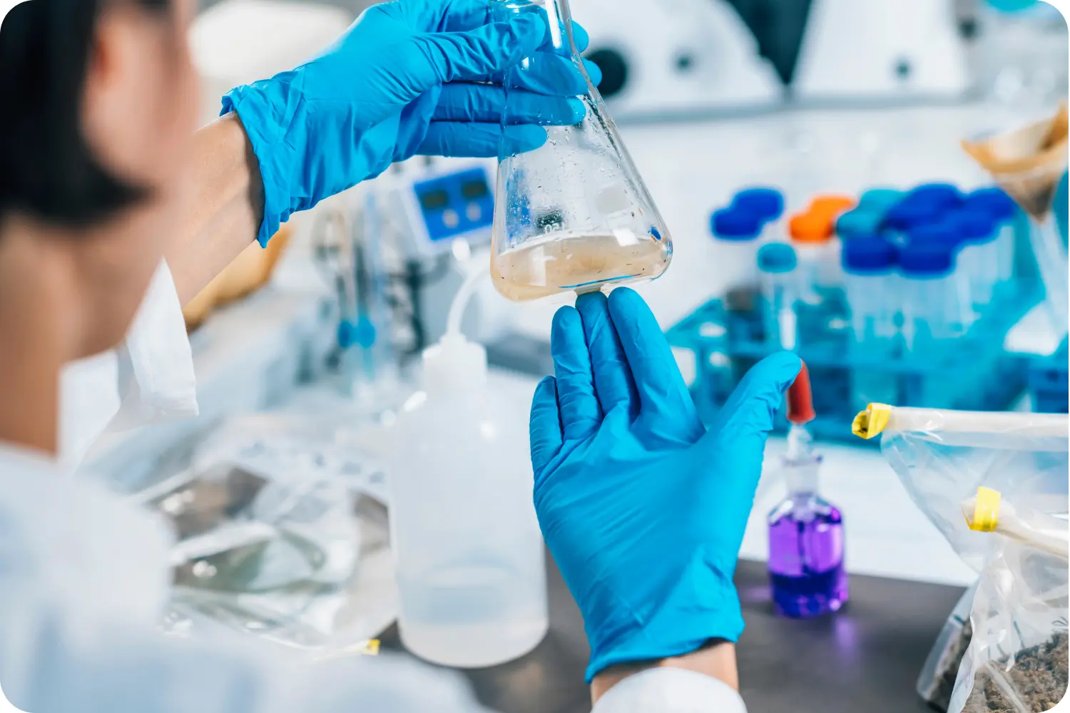 Technik laboratoryjny w niebieskich rękawicach bada próbkę mętnej wody
